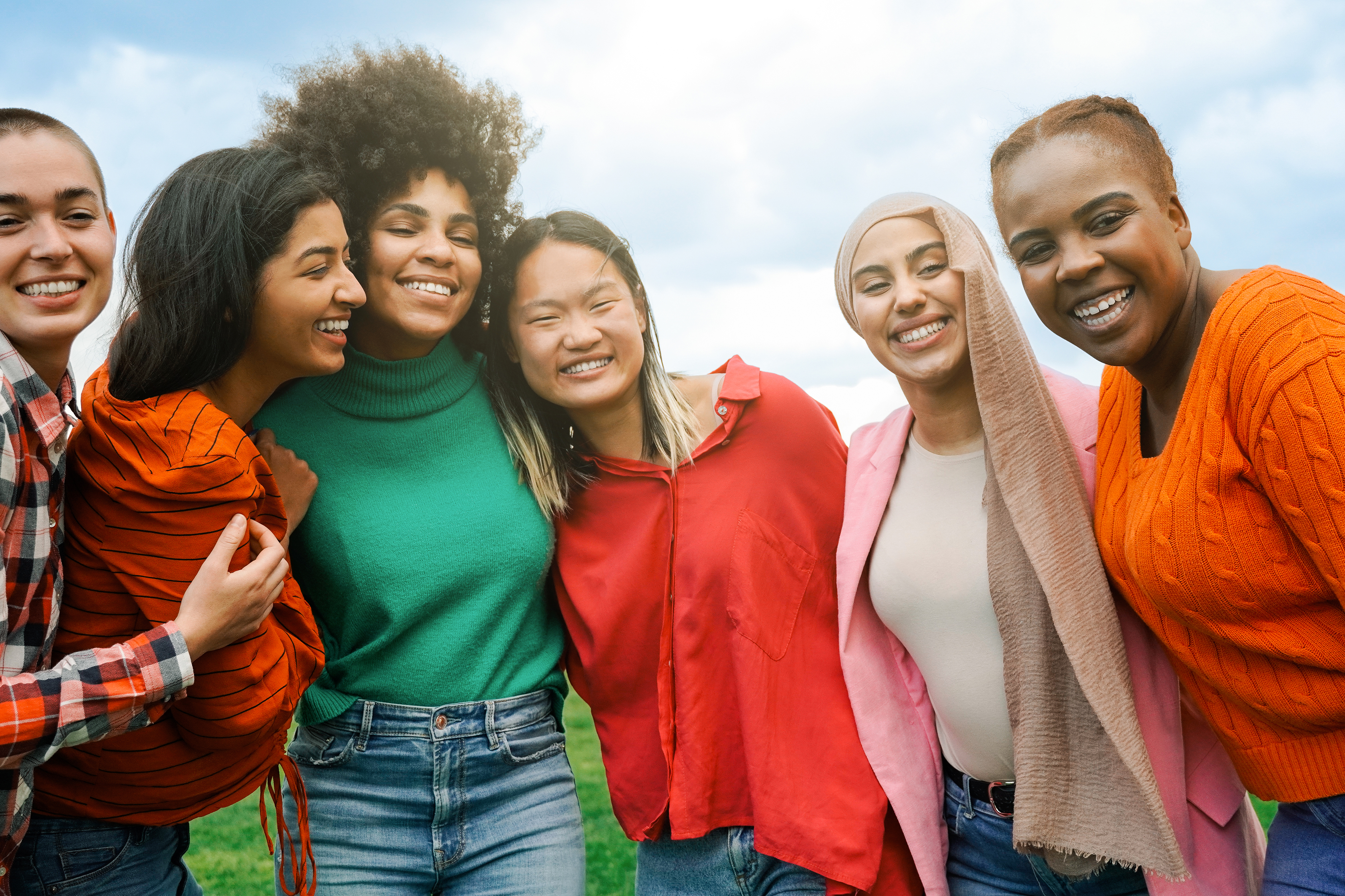 Multiracial group women friends hugging each other outdoors at park city - International people having fun smiling together - Focus on African curvy girl face